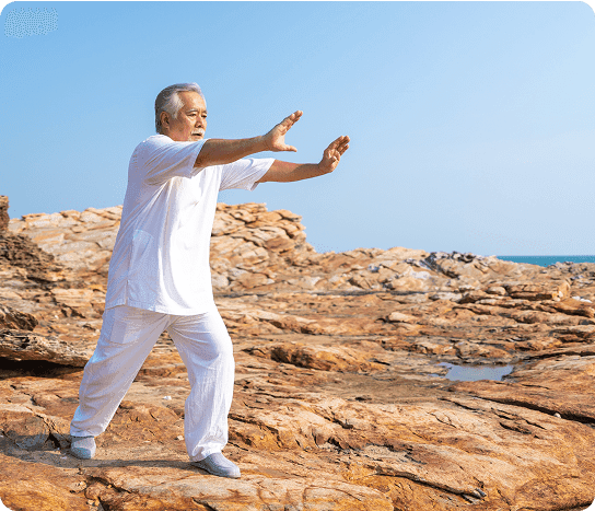Senior man practicing Tai Chi on rocky coastline